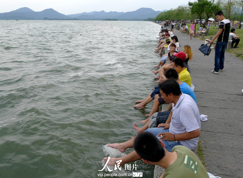 杭州西湖成了“洗腳池”。2013年7月21日,酷暑下的杭州猶如火爐一般,在白堤兩旁的西湖邊,一些不自覺的游客,脫去了鞋襪把腳浸入湖中,享受湖水帶來的涼爽。遠遠望去,美麗的西胡竟然成了天然的“洗腳池”,真是大煞風景。7月21日,一群游客坐在西湖邊洗腳納涼。施健學/人民圖片