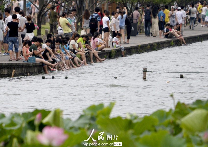 杭州西湖成了“洗腳池”。2013年7月21日,酷暑下的杭州猶如火爐一般,在白堤兩旁的西湖邊,一些不自覺的游客,脫去了鞋襪把腳浸入湖中,享受湖水帶來的涼爽。遠遠望去,美麗的西胡竟然成了天然的“洗腳池”,真是大煞風景。7月21日,一群游客坐在西湖邊洗腳納涼。施健學/人民圖片