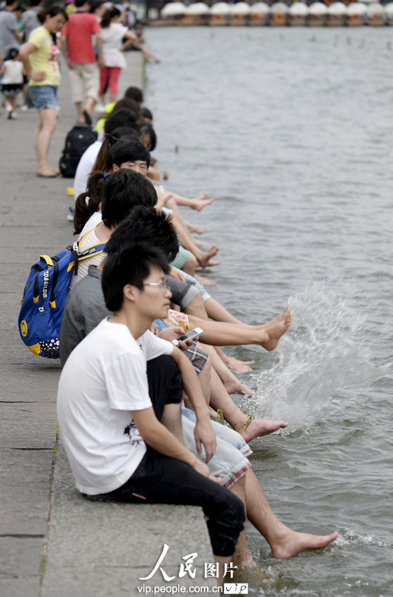 杭州西湖成了“洗腳池”。2013年7月21日,酷暑下的杭州猶如火爐一般,在白堤兩旁的西湖邊,一些不自覺的游客,脫去了鞋襪把腳浸入湖中,享受湖水帶來的涼爽。遠遠望去,美麗的西胡竟然成了天然的“洗腳池”,真是大煞風景。7月21日,一群游客坐在西湖邊洗腳納涼。施健學/人民圖片