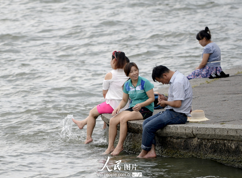 杭州西湖成了“洗腳池”。2013年7月21日,酷暑下的杭州猶如火爐一般,在白堤兩旁的西湖邊,一些不自覺的游客,脫去了鞋襪把腳浸入湖中,享受湖水帶來的涼爽。遠遠望去,美麗的西胡竟然成了天然的“洗腳池”,真是大煞風景。7月21日,一群游客坐在西湖邊洗腳納涼。施健學/人民圖片